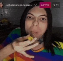 a woman in a rainbow shirt is drinking from a glass