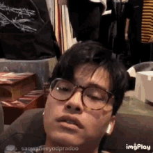 a young man wearing glasses and ear buds looks at the camera .