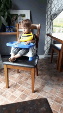 a baby is sitting in a high chair wearing a bib that says bee