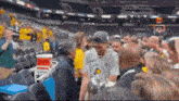 a man in a gray shirt is walking through a crowd of people in a stadium .