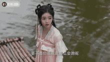 a girl in a pink dress is standing next to a river