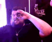 a man with a tattoo on his arm holds a glass in front of him