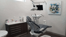 a dental office with a painting of flowers on the wall above the dental chair