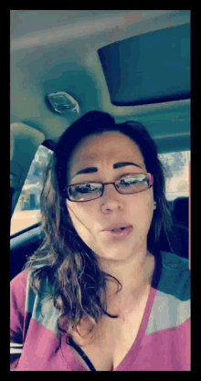 a woman with glasses is sitting in a car