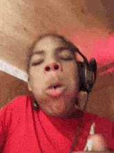 a person wearing headphones and a red shirt with a t on it