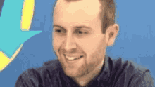 a man with a beard is smiling with a blue background .