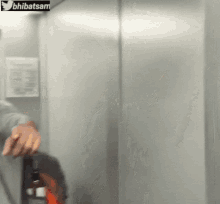 a person is standing in an elevator with a sign that says bhibatsam