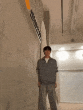 a man in a grey jacket is standing in front of a wall with a sign that says ' jcl ' on it