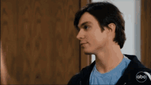 a young man in a blue shirt and black hoodie with the abc logo