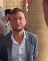 a man in a suit and white shirt is standing next to another man in glasses .