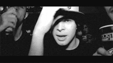 a black and white photo of a man wearing a hat in a crowd of people .