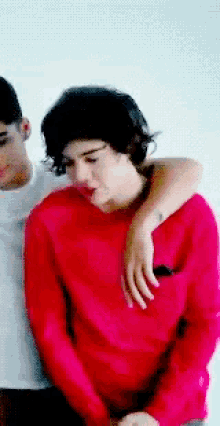 a man in a red sweater is sitting next to another man in a white shirt .