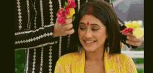 a man is putting flowers in a woman 's hair and smiling .