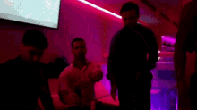 a group of men are dancing in a dark room with purple lights