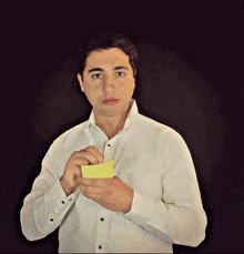 a man in a white shirt is holding a yellow sticky note in his hand