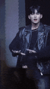 a young man in a black leather jacket is dancing on stage