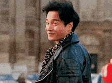 a man wearing a scarf and a leather jacket is smiling and looking over his shoulder