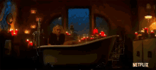 a man and a woman are taking a bath together in a bathtub surrounded by candles .