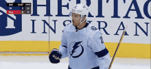 a hockey player stands on the ice in front of a heritage insurance sign