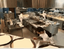 a man in a white apron is reaching for something in a large kitchen
