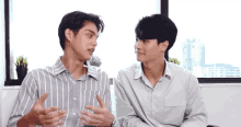 two men in striped shirts are sitting next to each other and talking