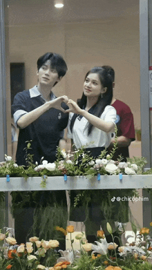 a man and a woman are making a heart with their hands