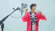 a man in a pink sequined jacket is singing into a microphone while holding a microphone