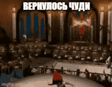 a man in a red hat is doing a trick on a stage in front of a crowd in a foreign language .