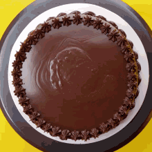 a chocolate cake with frosting on it is on a yellow surface