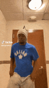 a man in a blue shirt is standing in front of a door in a bathroom .
