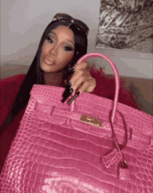 a woman is holding a pink handbag in her hand .