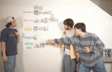 three men are standing in front of a poster that says major mid trash mega mid