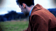 a man in a brown jacket looks down at something