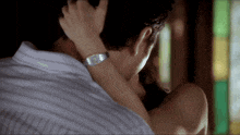 a man with a watch on his wrist holds a woman 's neck