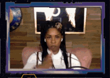 a woman is sitting in front of a screen with the letter p in the corner