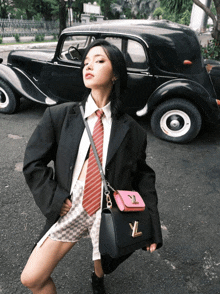 a woman in a suit and tie is holding a black bag with the letter yl on it