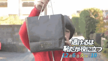 a person in a red sweater is holding a black bag with a sticker on it that says ' sunflower '