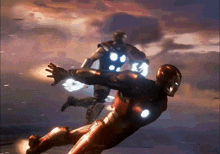 a man in a red suit is flying through the air while another man in a black suit stands behind him