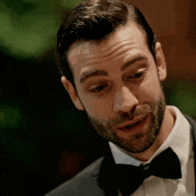 a man in a tuxedo and bow tie looks down