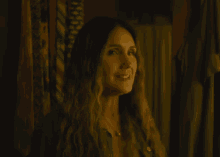 a woman with long hair and a necklace smiles