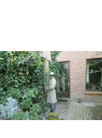 a man in a white coat and hat is standing in front of a brick building