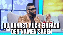 a man with a beard and sunglasses is sitting in a chair with the words du kannst auch einfach den namen sagen