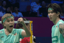 a man and a woman are playing badminton and the man is wearing a headband that says yonex on it