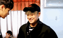 a man wearing a black hat with the letter m on it is smiling