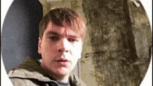 a young man in a jacket is looking at the camera in a room .