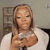 a woman in a white shirt is holding a cell phone in her hand .