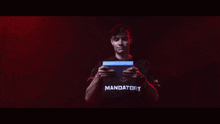 a man wearing a black shirt that says mandatory holds up his hands