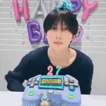 a boy is sitting in front of a birthday cake that says happy 27th
