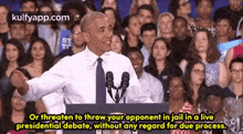 barack obama is giving a speech in front of a crowd while standing in front of a microphone .