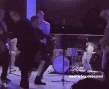 a group of people are dancing in a dark room and the words noelfisher.obsessed are above them